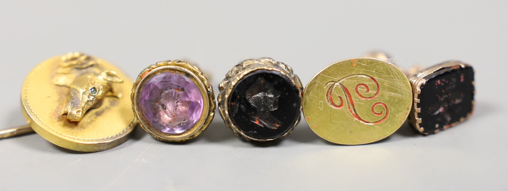 Three Victorian gilt metal fob seals, two set with bloodstone and carved with bust or bee, the other set with amethyst, a similar 9ct fob seal, a yellow metal horse head stick pin and a group of envelopes with wax seals.